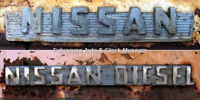 元中鉄バスのニッサンU690(1964年式,富士重工業)廃車体 (上側)ラジエーターグリル前面のエンブレムと(下側)フロント フェンダー側面のエンブレム