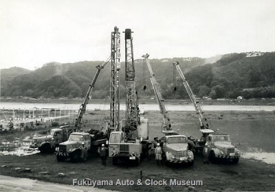 福山市本庄町(現 南本庄四丁目)の芦田川左岸河川敷で昭和40年頃に撮影されたクレーン車・杭打車の並び写真【クリックで大きく表示】