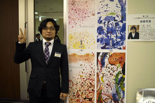 作品前でピースサインの工藤さん