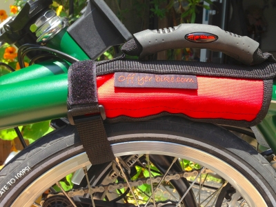 ブロンプトンのフレームに取り付けたオフヤーバイクのキャリングハンドル。面ファスナーを延ばしてタイヤに巻き付けている