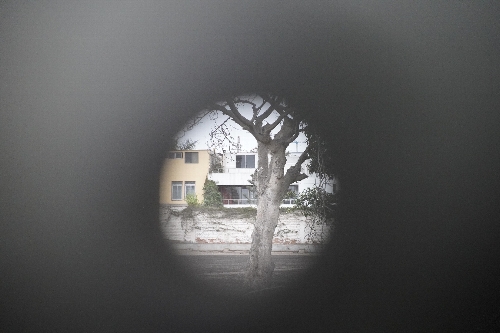旧日本大使公邸跡の門の扉に空いたままとなっている銃弾による穴から中を眺める