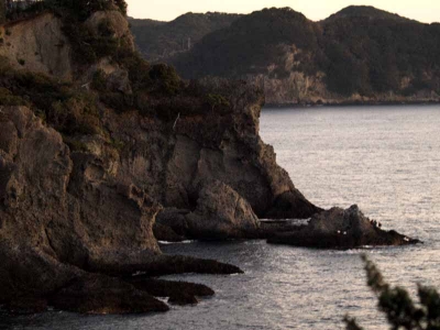 崖の下の岩の上の釣り人