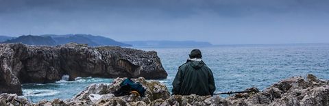 暗い海の見える岩場に座っている人の写真