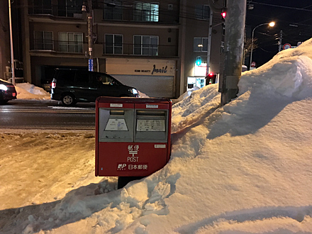 除雪されて道端に積まれた雪、郵便ポストのところだけは雪の壁が切れている
