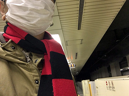マスク姿で地下鉄の駅のホームに立つ